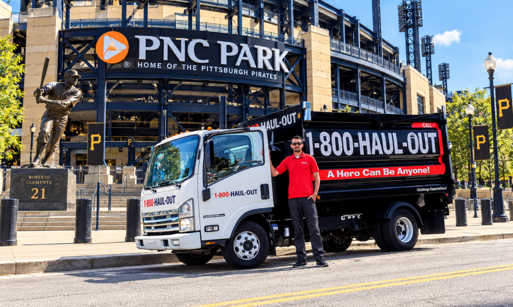 Aleksandr Kukota beside a 1-800-Haul-Out truck with PNC Park in the background