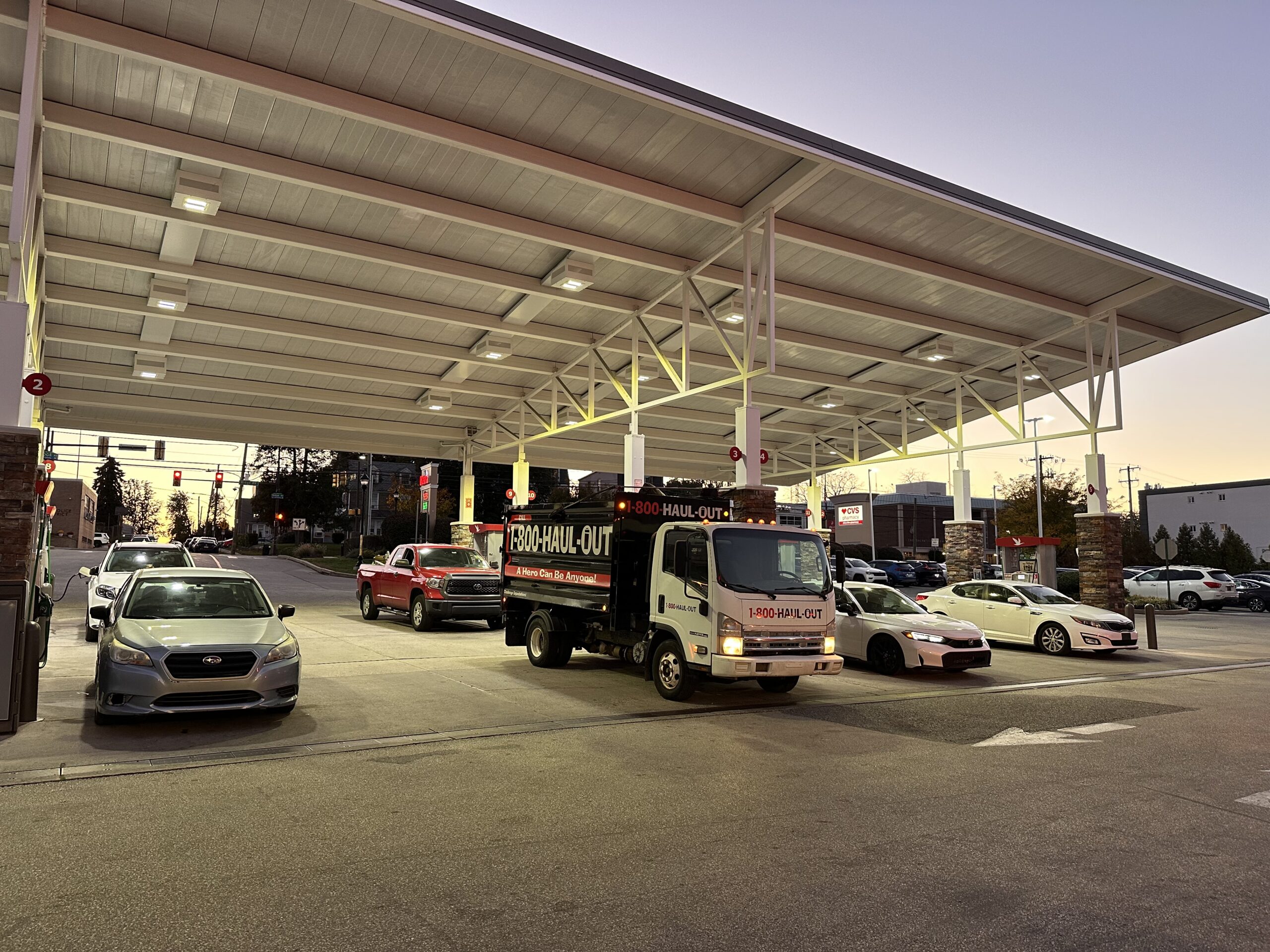 1-800-Haul-Out truck under the illuminated canopy at a local Wawa at dusk.